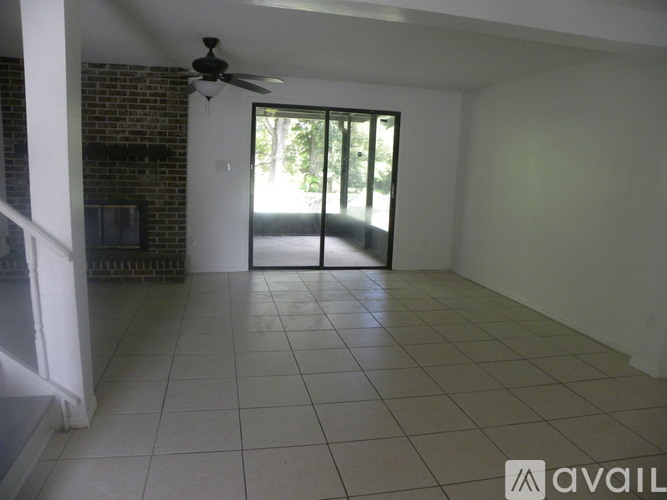 A room with a ceiling fan and sliding glass doors leading to a backyard.