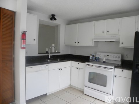 A kitchen with white cabinets and black countertops.