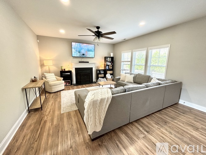 A living room with a grey couch, a fireplace, and a television on the wall.