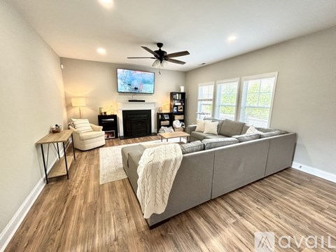 A living room with a grey couch, a fireplace, and a television on the wall.