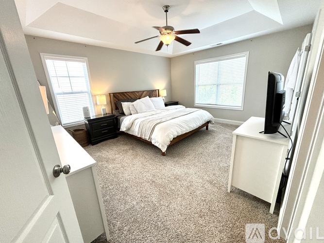 A bedroom with a bed, a dresser, and a ceiling fan.
