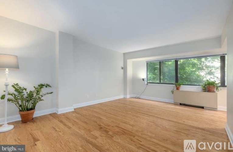 A room with wooden flooring and a window with a view of trees.
