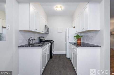 A kitchen with white cabinets and a black countertop.