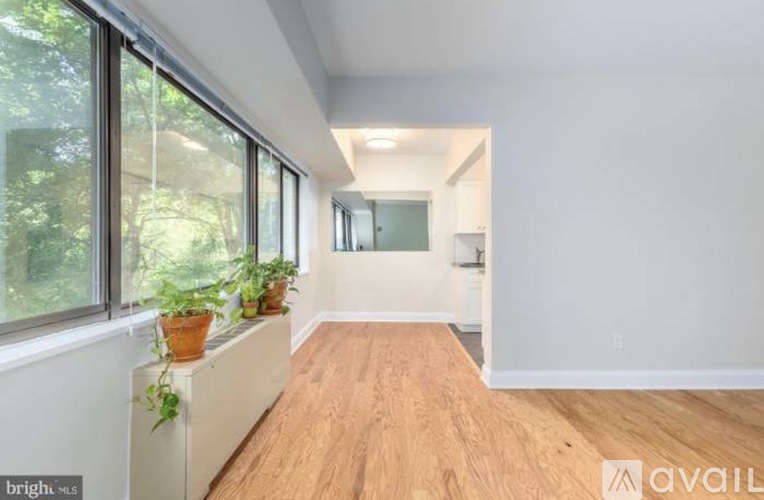 A room with wooden floors and white walls, with a window on the left side.