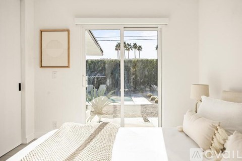 A bedroom with a large bed and a view of a patio with a cactus.