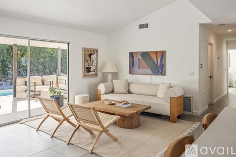 A modern living room with a white sofa, wooden coffee table, and a painting on the wall.