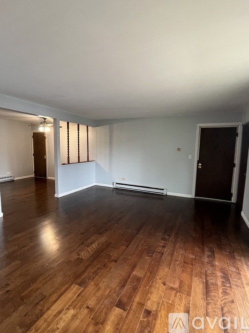 A room with wooden flooring and a door on the right side.