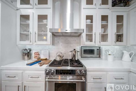 A modern kitchen with white cabinets and a stainless steel stove top.