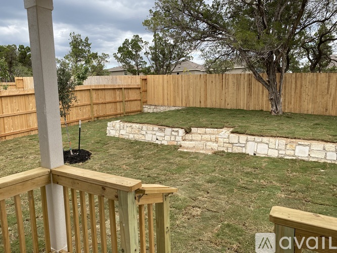 A backyard with a wooden fence and a small tree.