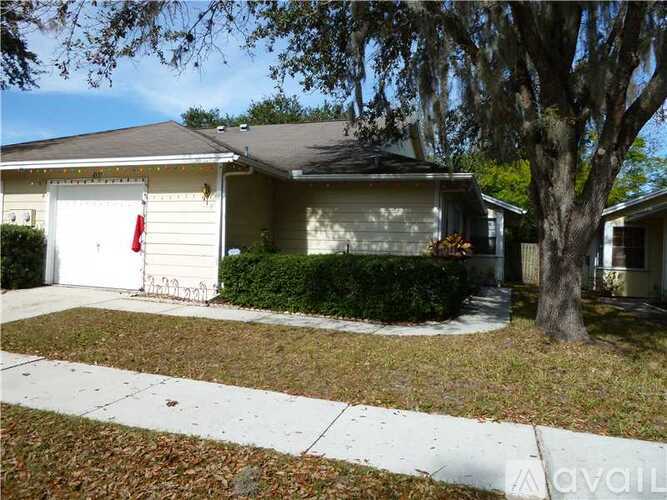 A house with a white garage door and a tree in front.