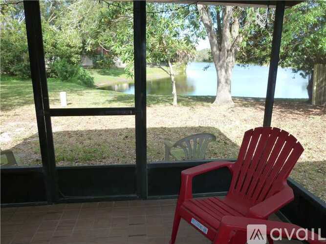 A red chair is on a balcony overlooking a body of water.