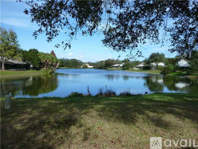 A serene lake surrounded by lush greenery and trees under a clear blue sky.