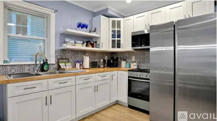 A kitchen with white cabinets and a stainless steel refrigerator.