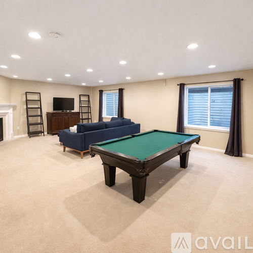A pool table is in the middle of a room with a blue sofa and a television.