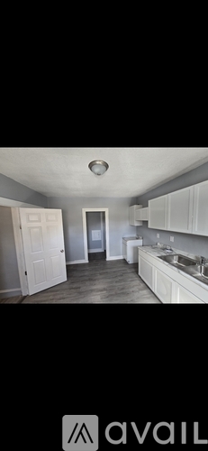 A kitchen with white cabinets and a wooden floor.