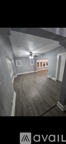 A room with a ceiling fan and wooden flooring.