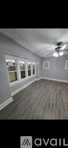 A room with a ceiling fan and wooden flooring.