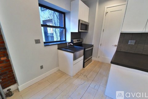A kitchen with white cabinets and a black countertop.