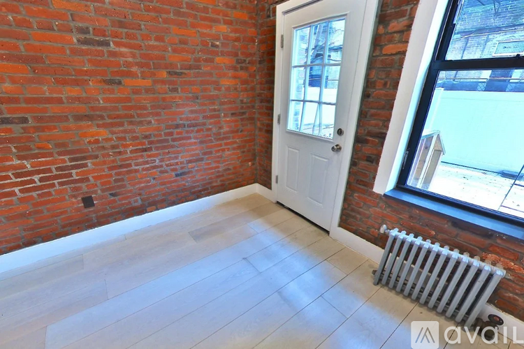 A room with a white door and a window with a view of a building outside.