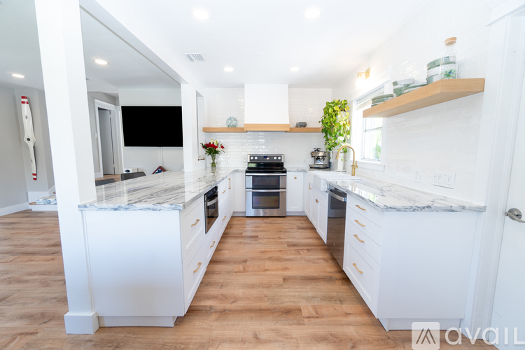 A kitchen with white cabinets and a wooden floor.