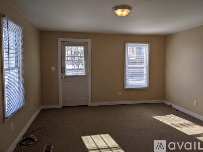 A room with a door, a window, and a carpeted floor.