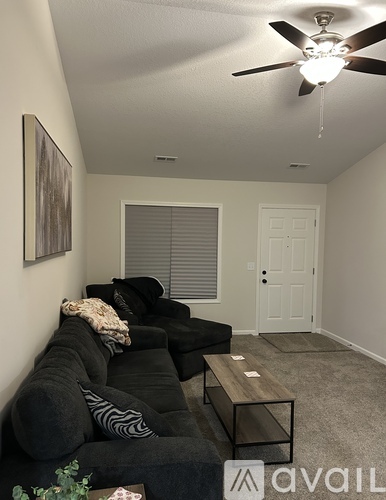 A living room with a black couch and a ceiling fan.