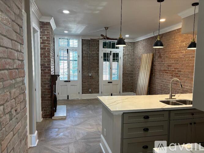 A kitchen with a white countertop and a brick wall.