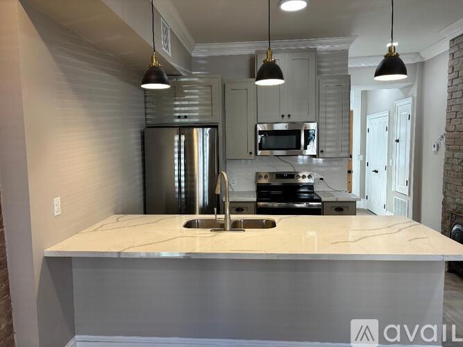 A kitchen with a marble countertop and a stainless steel refrigerator.