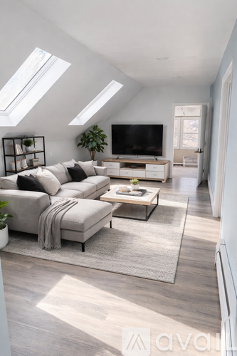 A living room with a grey sofa and a grey rug.