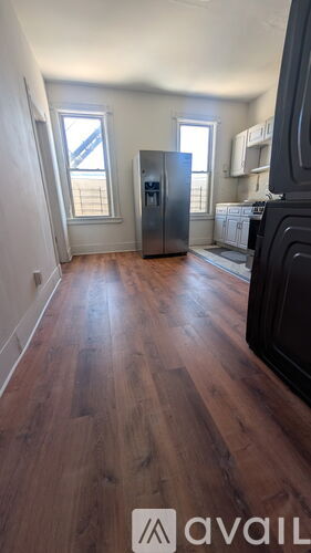 A kitchen with a refrigerator and wooden floors.