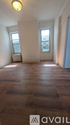 A room with wooden floors and two windows.