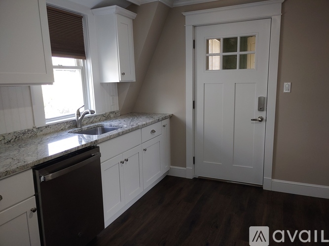 A kitchen with white cabinets and a black dishwasher.