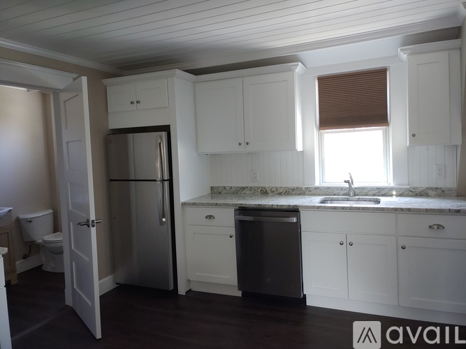 A kitchen with white cabinets and a stainless steel refrigerator.