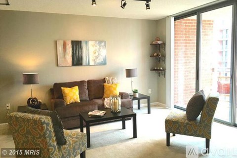 A living room with a brown couch and a painting on the wall.