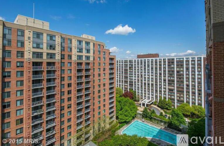 A tall red brick building with a pool in front.
