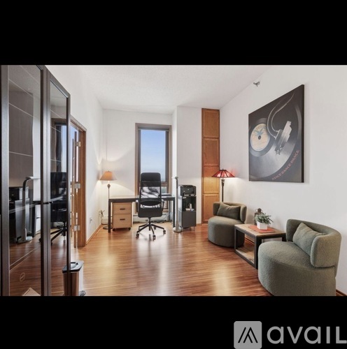 A modern living room with a grey couch and a painting on the wall.