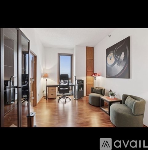 A modern living room with a grey couch and a painting on the wall.