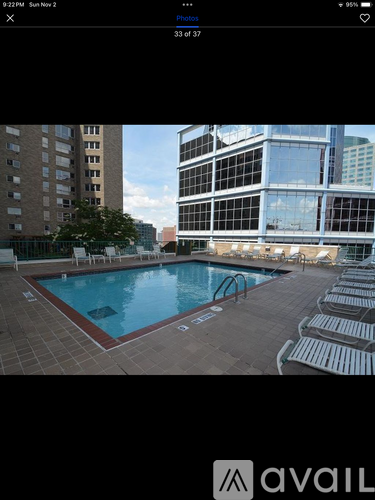 A pool surrounded by chairs in a city setting.