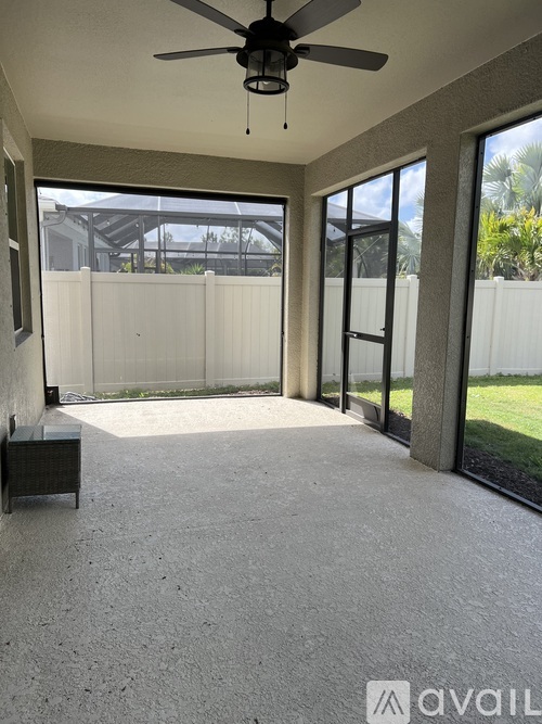 A spacious room with a ceiling fan and sliding glass doors leading to a backyard.