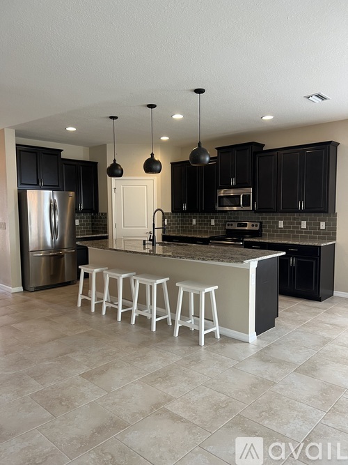 A kitchen with black cabinets and a white island.