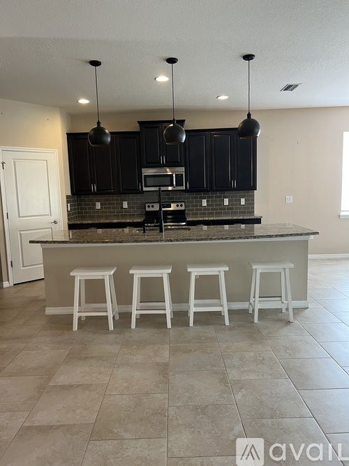 A kitchen with a bar area and four stools.