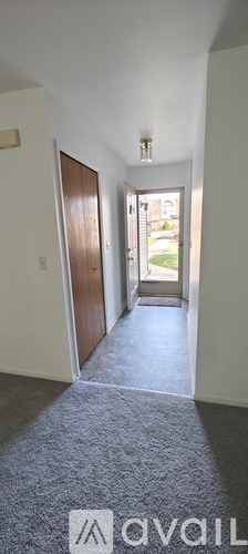A hallway with a carpeted floor and a door on the left.