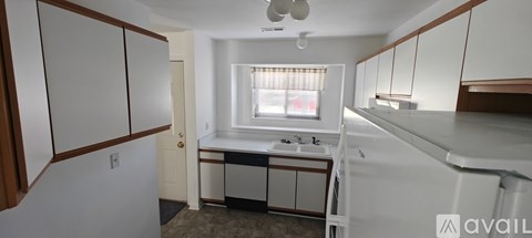 A kitchen with white cabinets and a window.
