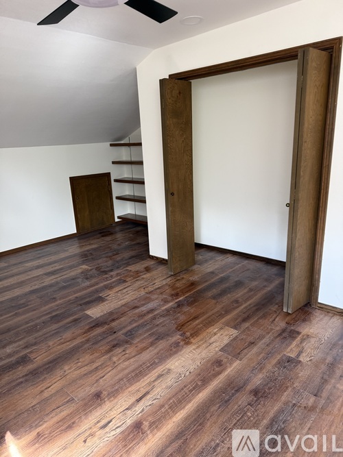 A room with wooden flooring and a ceiling fan.