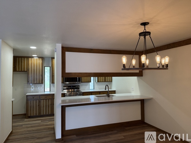 A modern kitchen with a large island and pendant lights.