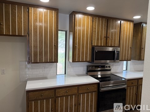 A kitchen with wooden cabinets and a stainless steel oven.