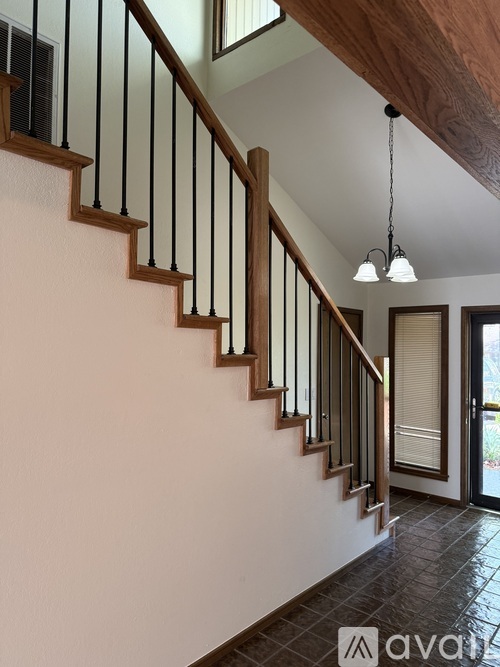 A staircase with a wooden handrail and black balusters leads to a doorway.