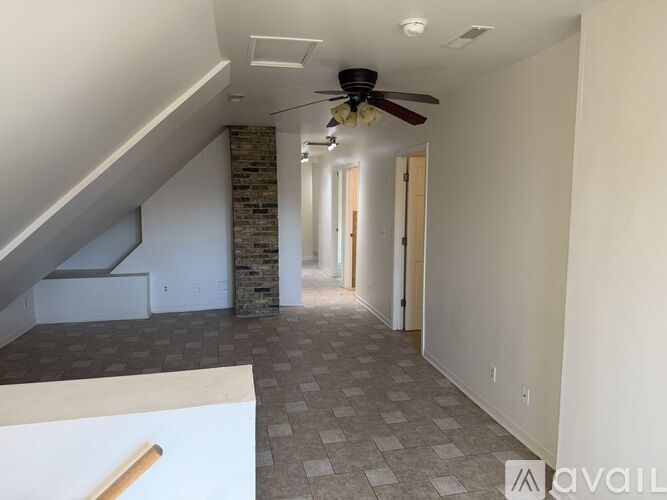 A spacious room with a ceiling fan and a stone pillar.