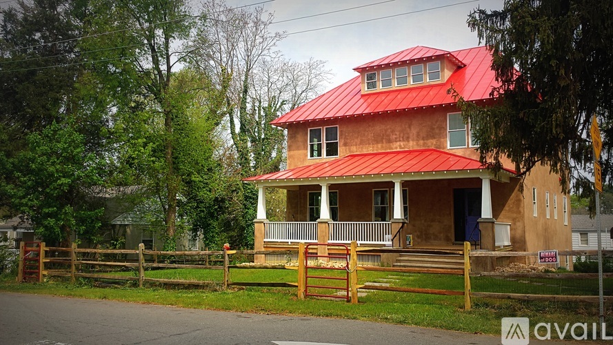 A house with a red roof and white trim is for sale.