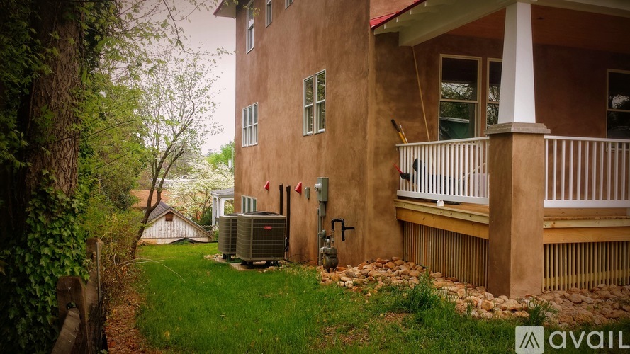 A brown house with a balcony and a tree in front.